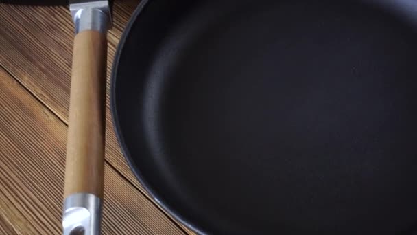 Two new non-stick cast iron pans on a wooden background. Grill pan with wooden handle, cooking accessories — Stock Video