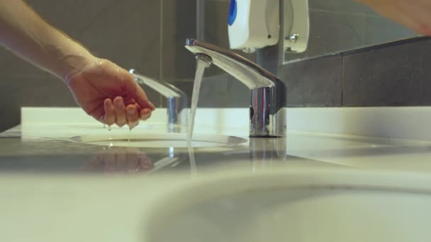 Egy férfi kezet mos egy nyilvános WC-ben szappannal, belsővel. A baktériumok és fertőzések elleni védelem fogalma, higiénia, kovid-19 — Stock videók