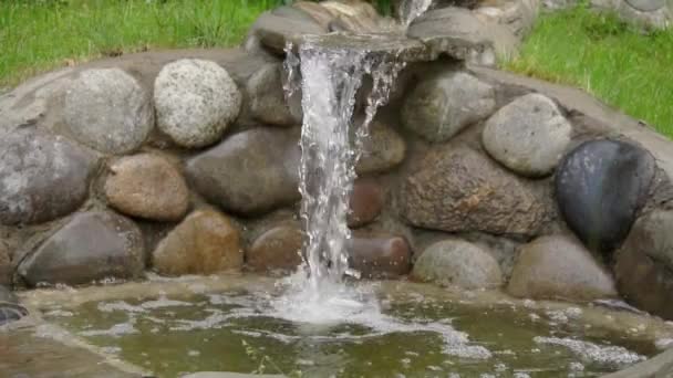 Искусственный водопад, созданный руками человека. Вода стекает по камням в пруд, озеленяя. Предпосылки для медитации и релаксации, замедленного движения — стоковое видео