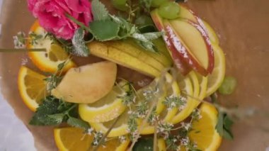 Ahşap bir arka planda güzel bir meze, nane ve limonlu armut dilimleri, pembe bir çiçek ve açık büfe ile süslenmiş.