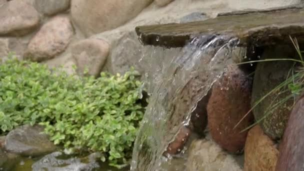 Een kunstmatige waterval gemaakt door mensenhanden. Water stroomt de stenen in de vijver, landschapsarchitectuur. Achtergrond voor meditatie en ontspanning, slow motion — Stockvideo