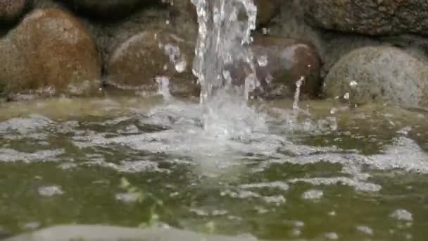 Het water stroomt van de stenen in de vijver. Kleine kunstmatige waterval, rust en meditatie, achtergrond voor tekst, slow motion — Stockvideo