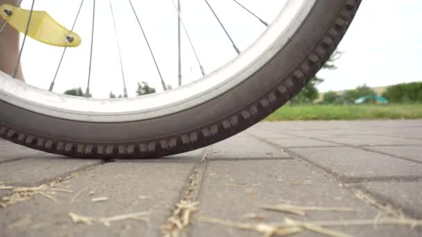 Een fietser rolt een fiets met een vlak, doorboord wiel, close-up. Buizen voor stanswielen, industrie — Stockvideo