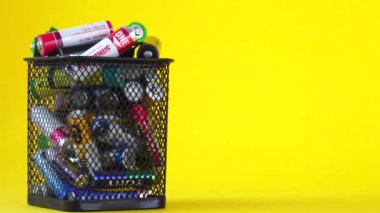 BOBRUISK, BELARUS 10.08.2020: Sarı zemin üzerinde atık pilleri olan sepet. Pil geri dönüşüm konsepti, iş yeri, metin için kopyalama alanı