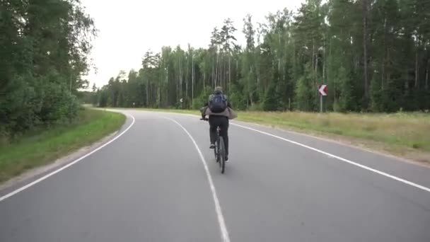 Muž s batohem na zádech jezdí na silnici na pozadí slunce, cestování a sportu, tempo — Stock video