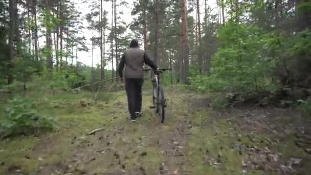 O cara rola a bicicleta através da floresta contra o fundo de árvores densas. Conceito de estilo de vida saudável, descanso na floresta — Vídeo de Stock
