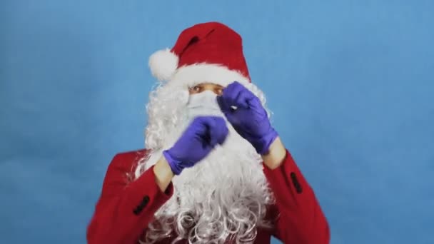 Mann wie ein Weihnachtsmann tanzt in Schutzmaske und Handschuhen. Coronavirus COVID und Neujahr, Weihnachten Konzept. Pandemie — Stockvideo