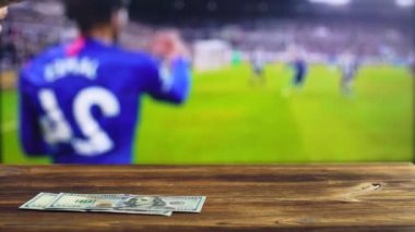 Bir adam televizyondaki bir futbol maçının arka planında dolar sayar. Bahisçi ve spor bahisleri kavramı, metin için kopyalama alanı