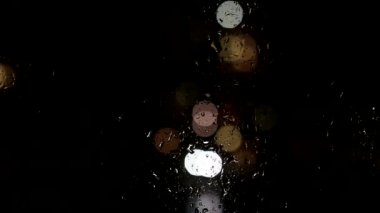 Pencerenin camında yağmur damlaları, pencerenin dışında araba süren cadde, kötü hava. Arkaplan, metin için boşluk kopyala, gece