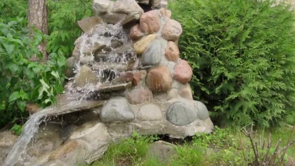 Sztuczny wodospad stworzony przez ludzkie ręce. Woda spływa kamieniami do stawu, tworząc krajobraz. Tło medytacji i relaksu, zwolnione tempo — Wideo stockowe