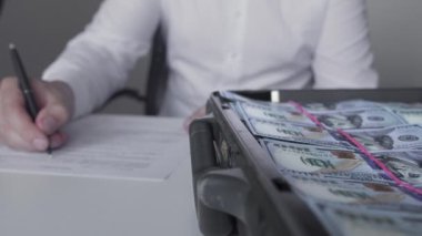 Adam içi para dolu bir kasanın yanında kontrat imzalıyor. Başarılı bir anlaşma. Rüşvet, yolsuzluk konsepti. Finans ve yatırım. Beyaz gömlekli bankacı ofiste oturuyor. Zenginlik