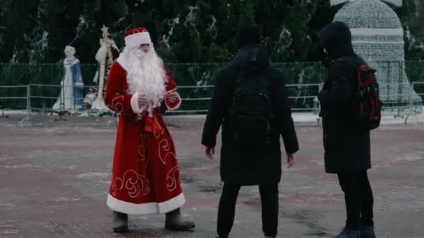 Ruský Ded Moroz jako Santa Claus bojuje s kolemjdoucími na náměstí MINSK, BELARUS 12.20.19. Agresivní a naštvaný animátor na Silvestra a Vánoce. Akční potřesení rukou — Stock video