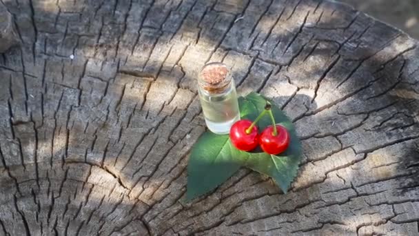 Butelka z olejkiem wiśniowym na drewnianym tle. Koncepcja olejków aromatycznych wiśni w terapii i kosmetologii, przestrzeń do kopiowania — Wideo stockowe