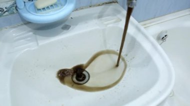 Paslı ve kirli su musluktan lavaboya akar. Musluk suyunun arındırılması, ana su şebekesinin onarımı, sanayi