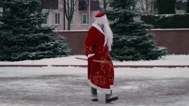 El ruso Ded Moroz como un Santa Claus camina por la plaza central de la ciudad. Navidad y Año Nuevo concepto. Tipo delgado con bastón — Vídeos de Stock