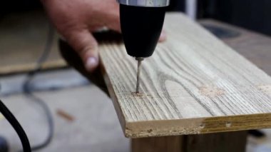 Bir adam, yakın plan bir ülke sandalyesi yapmak için tahta bir panele delik açıyor. El yapımı, profesyonel.