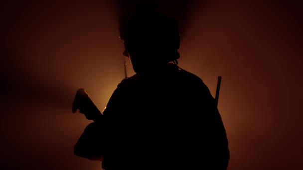 Soldado militar en equipo militar con un arma de fuego en humo sobre un fondo negro. Contraluz, operaciones militares, lento mo — Vídeos de Stock