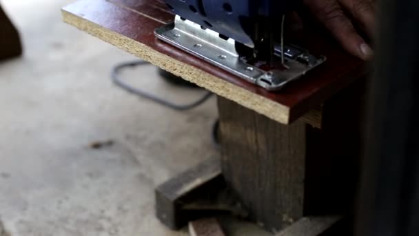 Un hombre corta un pedazo de madera con un rompecabezas para hacer muebles en el campo, un hobby, primer plano — Vídeos de Stock