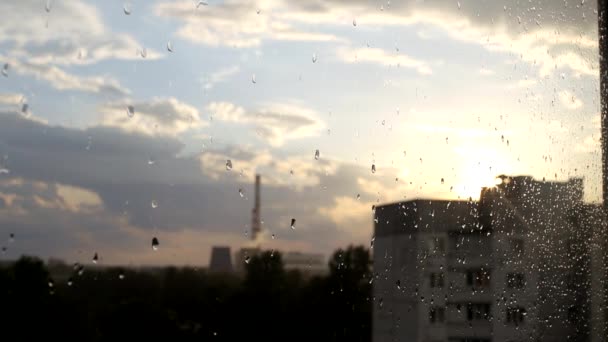 Blick aus dem Fenster des Hauses, draußen regnet es und im Hintergrund scheint die untergehende Sonne. Kopierraum für Text — Stockvideo