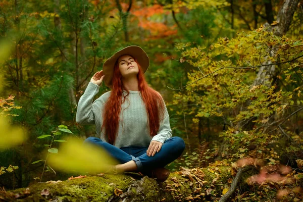 Unga rödhårig kvinna sitter i höst park — Stockfoto
