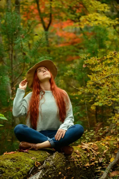 Jonge roodharige vrouw zitten in de herfst park — Stockfoto