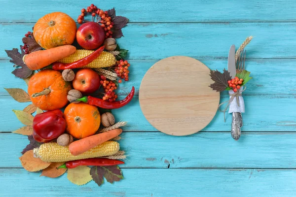 Autumn background set, fallen leaves, fruits, vegetables, wooden table. Seasonal side composition, vintage round cutting board, copy space. Thanksgiving food, healthy and fresh, top view, flat lay.