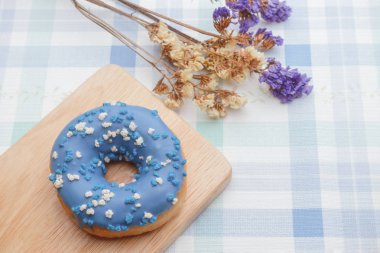 Ahşap plaka üzerinde sprinkles ile mavi buzlu dougnut.