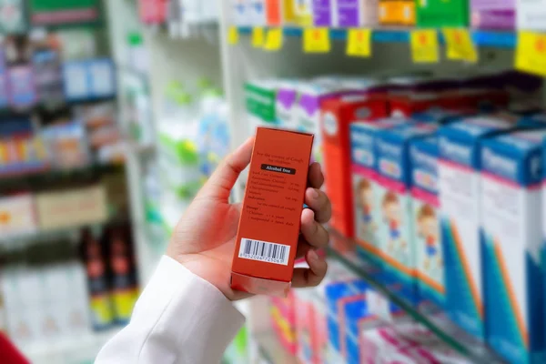 Eczacı eczane bir kırmızı ilaç kutusundan barkod üzerinde fiyat arıyorsunuz