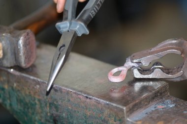 Demirci demircideki aletlerle çalışır, fırından yeni çıktı.,