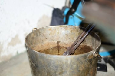 Demirci demircideki aletlerle çalışır, fırından yeni çıktı.,