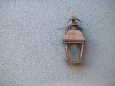 Beyaz duvarda bir evin dışına bağlı rustik bakır lamba