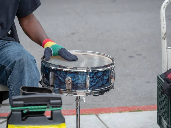 Drummer beats on steel drum on sidewalk in a street performance outside