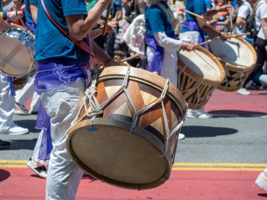 A mexican marching band beats on drums while walking down streets of Carnaval festival clipart