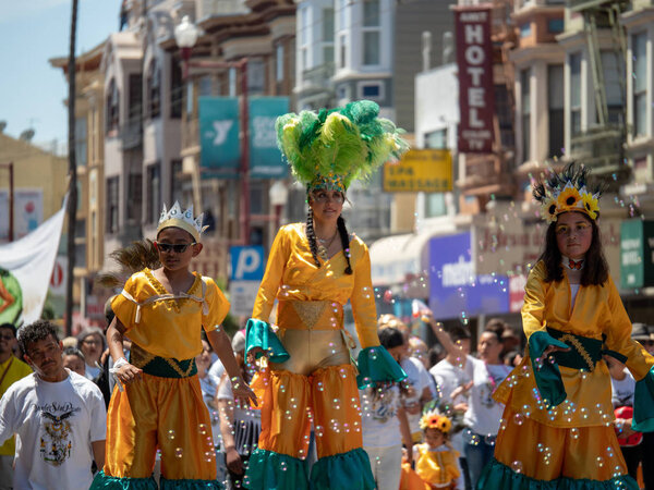 САН-ФРАНЦИСКО, Калифорния 27 мая 2014 года - Женщина на ходулях и мексиканская праздничная одежда прогуливается по улице на карнавальном фестивале
