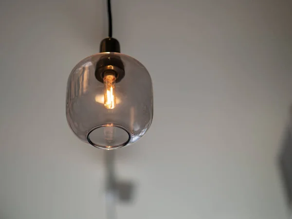 Stylish incandescent lightbulb enclosed in glass hanging from ce — Stock Photo, Image