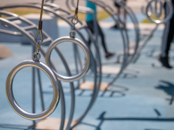 Anillos gimnásticos de acero suspendidos en un gimnasio al aire libre con copia — Foto de Stock