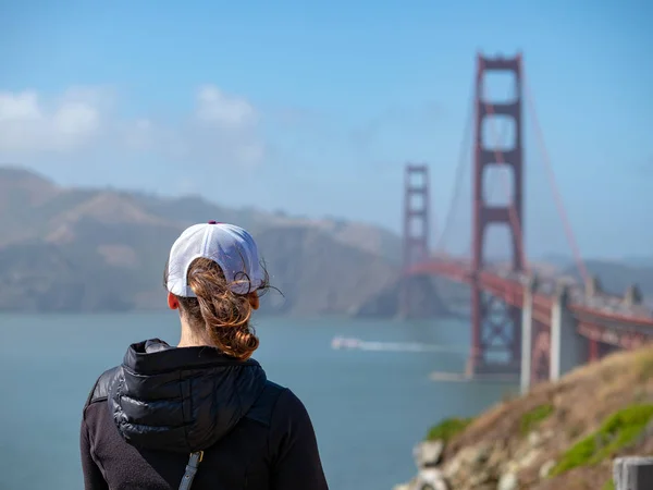 Vista trasera de la mujer en gorra de béisbol mirando hacia fuera en Golden Gate Bri — Foto de Stock