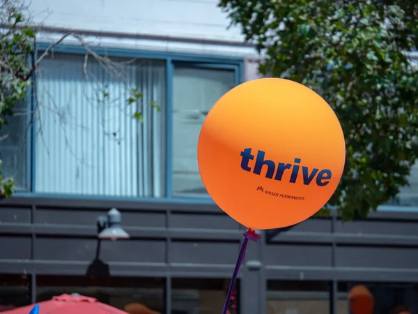 Naranja Kaiser Permanente prosperar globo volando en una zona urbana — Foto de Stock