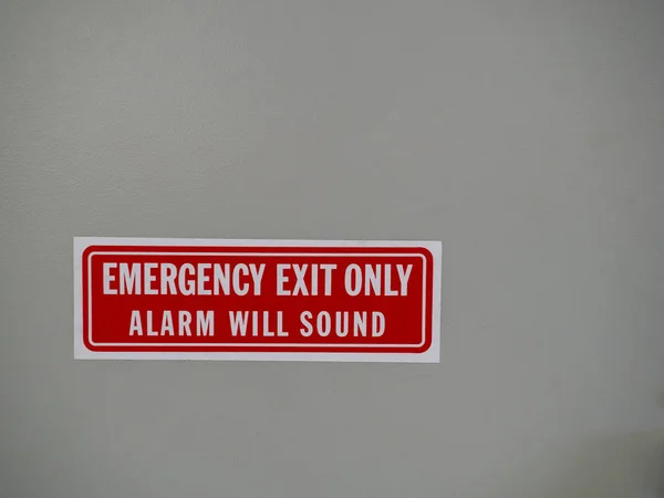 Saída de emergência apenas, o alarme soará sinal postado em uma porta branca — Fotografia de Stock
