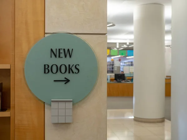 Nuevo signo de libros apuntando a la derecha con biblioteca en segundo plano — Foto de Stock