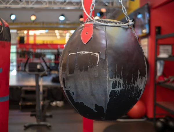 Bolso pesado estilo bola de demolición de cuero negro usado colgado en un gimnasio de boxeo — Foto de Stock