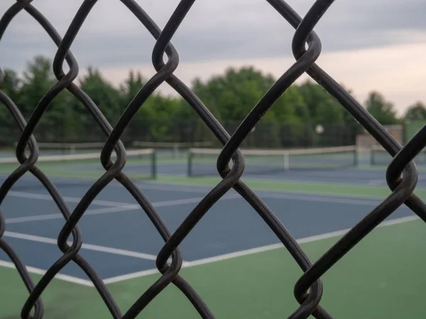 Canchas de tenis en segundo plano con marco de valla negra en primer plano — Foto de Stock