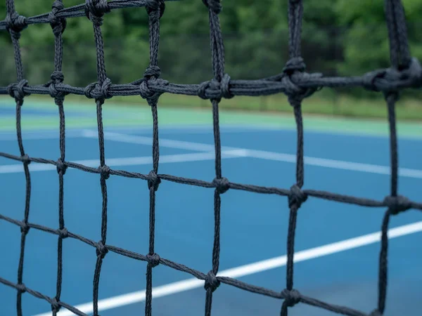 Vista ampliada de la malla de red de canchas de tenis con pistas borrosas en segundo plano — Foto de Stock