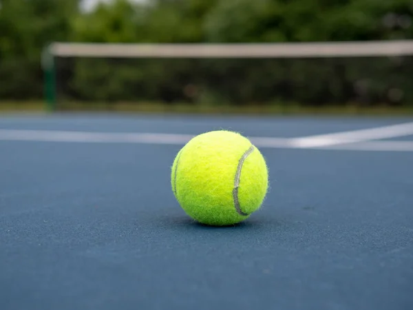 Pelota de tenis sentada en la cancha de tenis local azul con vista cerca del suelo — Foto de Stock