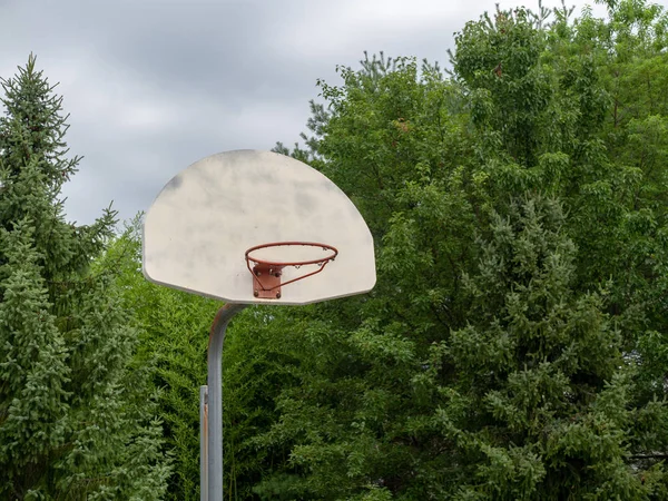 Rundown steel basketball hoop missing its net on overcast day — Stock Photo, Image