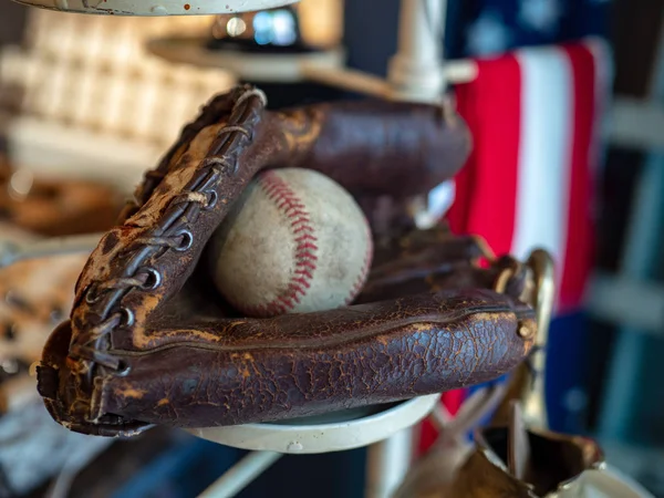 Бейсбол, сидячи в старі старомодні рукавичка з американським прапором у фоновому режимі — стокове фото