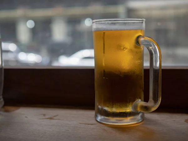 Stora frostiga öl mugg fylld med lager som sitter på bänk — Stockfoto