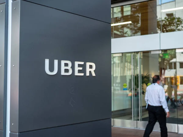 Cartel de entrada a la oficina de la sede de Uber con hombre caminando dentro Imagen De Stock