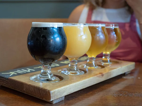 Flight of stout, Amber, IPA beers sitting on wooden paddle — Stock Photo, Image