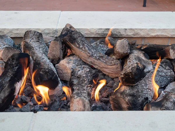 Troncos sentados en fuego abierto en un hoguera de piedra blanca — Foto de Stock